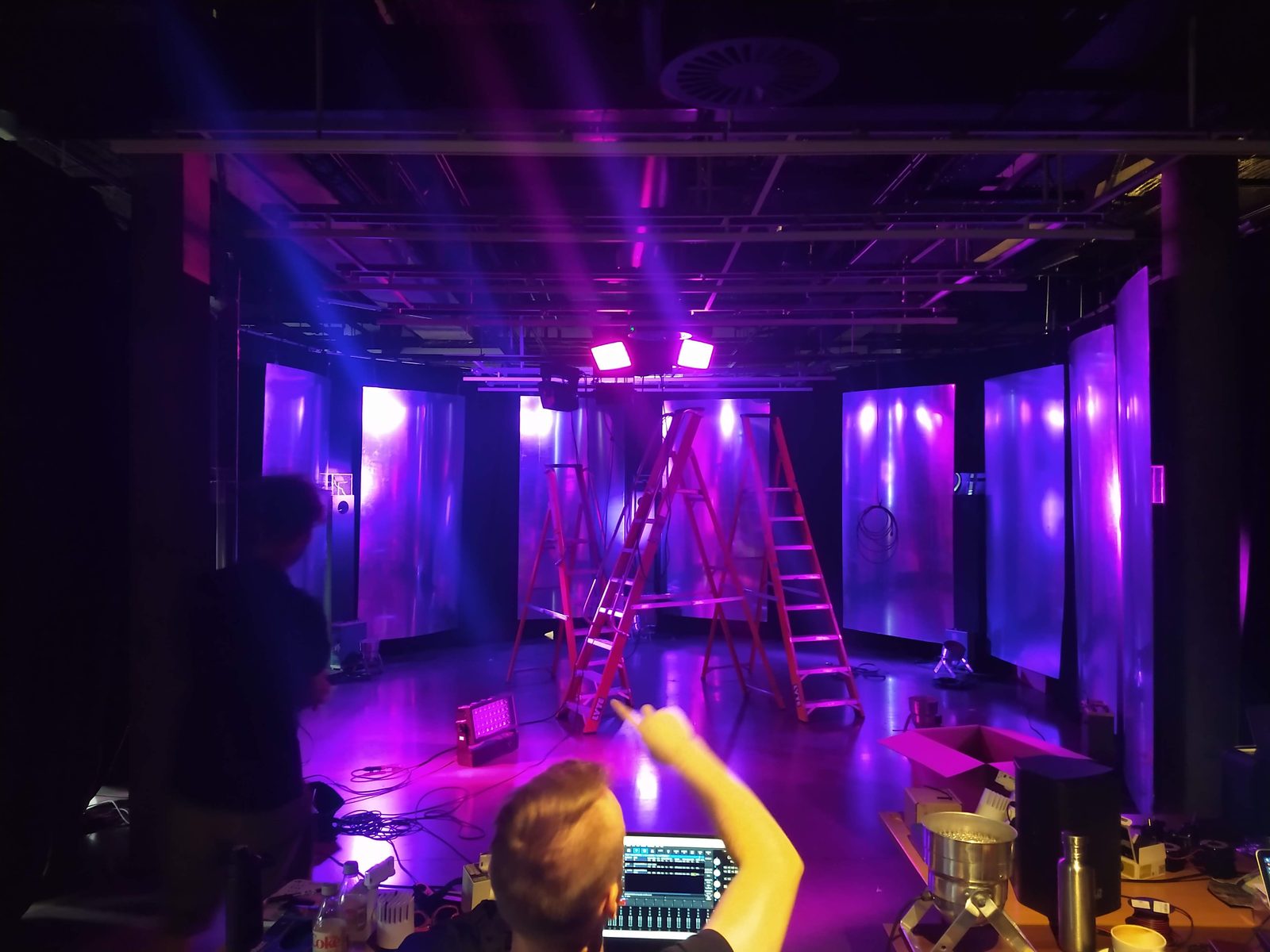 Testing Ground mid-install: lighting rig, ladders and a control desk under coloured light